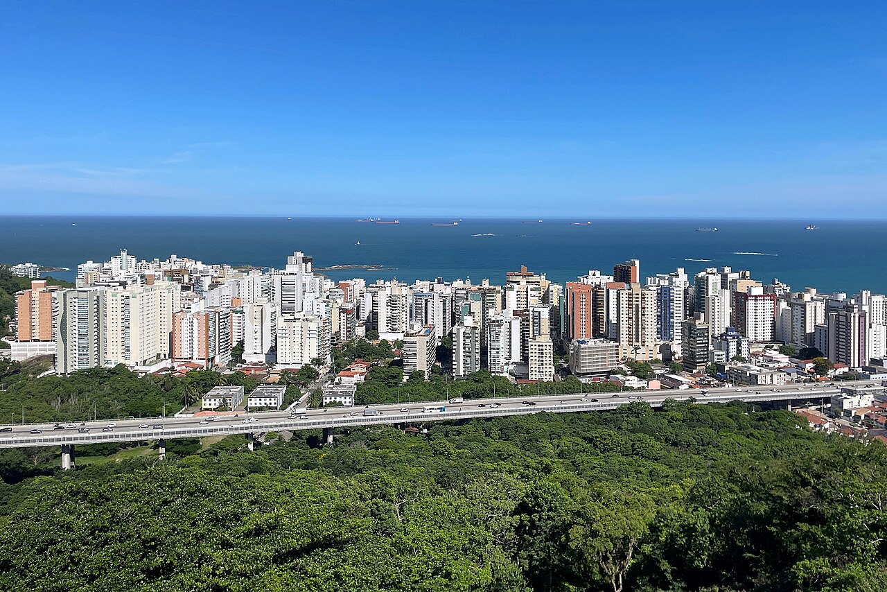 Vista do bairro Praia da Costa, em Vila Velha, Espírito Santo, a partir do Convento da Penha, com prédios, o mar ao fundo e o viaduto de acesso à Terceira Ponte sobre a mata